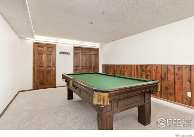 rec room with a wainscoted wall, billiards, a textured ceiling, wooden walls, and light colored carpet