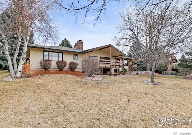 rear view of property with a wooden deck, a lawn, and a chimney