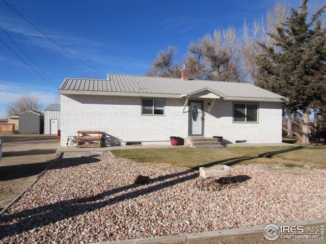 ranch-style home with a chimney and metal roof