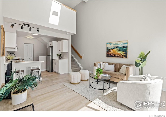 living room with stairway, visible vents, baseboards, and light wood-style floors