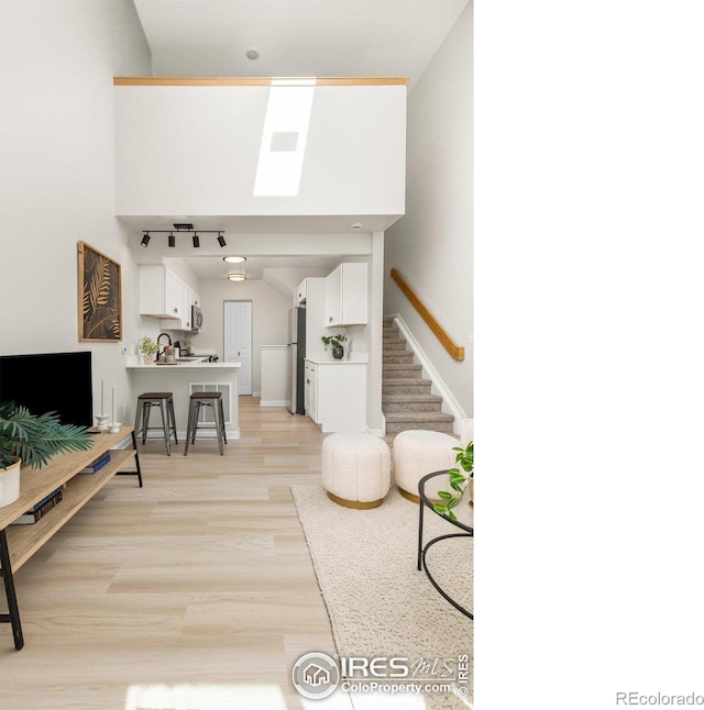 living area with baseboards, stairs, and light wood-style floors