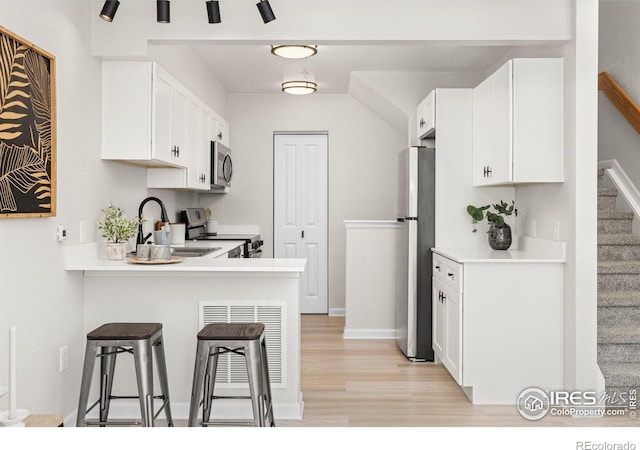 kitchen with appliances with stainless steel finishes, a breakfast bar area, and white cabinets