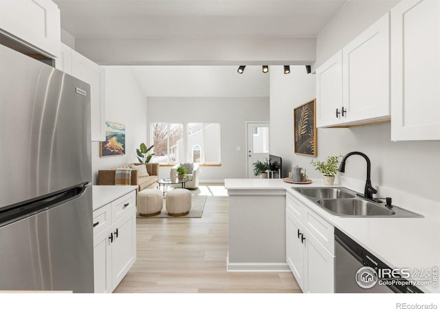 kitchen with open floor plan, light countertops, freestanding refrigerator, white cabinets, and a sink