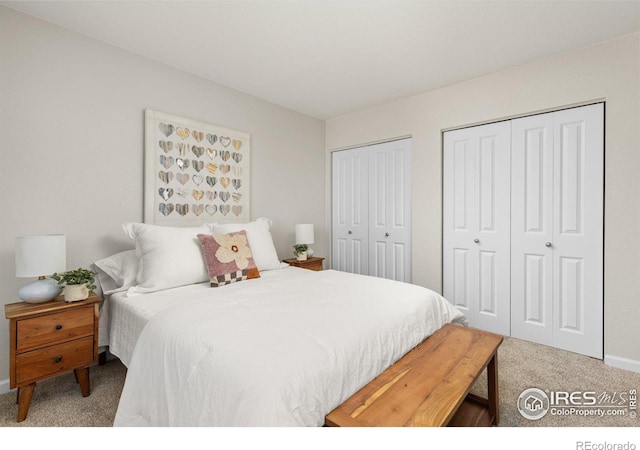 carpeted bedroom with baseboards and two closets