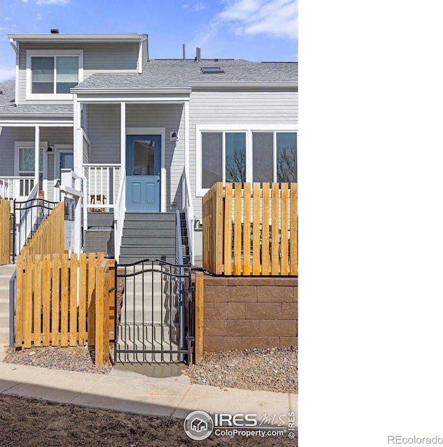 view of front of home with a fenced front yard, a porch, and a gate