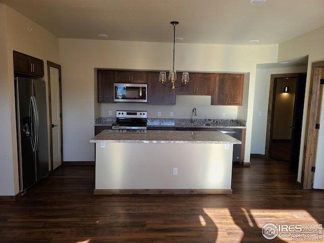 kitchen featuring dark wood finished floors, a sink, dark brown cabinetry, appliances with stainless steel finishes, and a center island