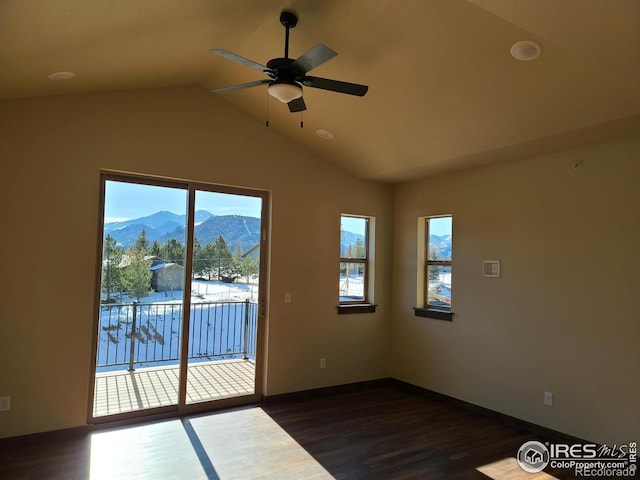 empty room featuring ceiling fan, a mountain view, lofted ceiling, and dark wood-style flooring