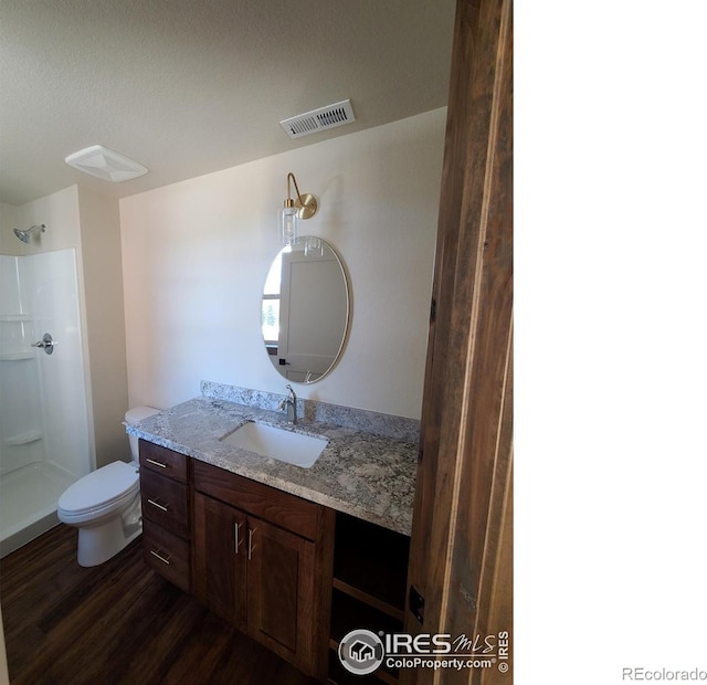 bathroom with vanity, wood finished floors, visible vents, a shower, and toilet