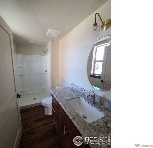 full bath with vanity, toilet, a shower, and wood finished floors