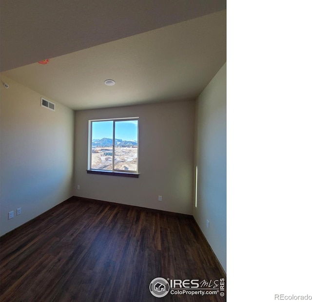 empty room with visible vents and dark wood-type flooring