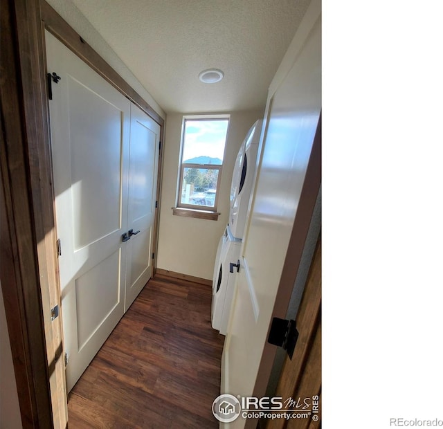 hallway with dark wood finished floors, a textured ceiling, and stacked washing maching and dryer