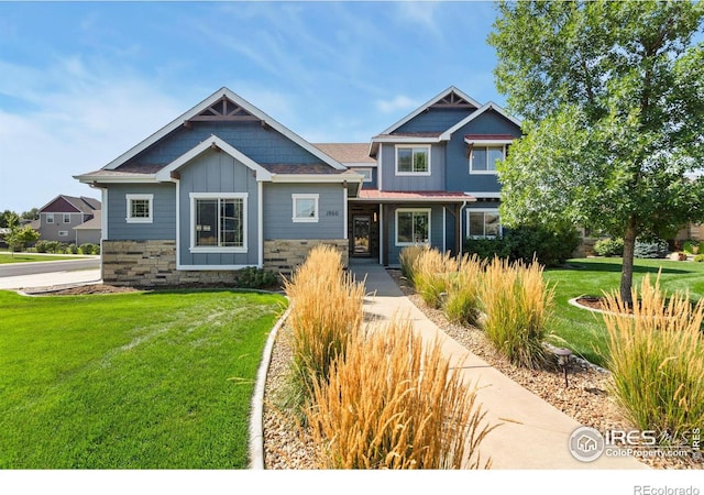 craftsman-style house featuring stone siding, board and batten siding, and a front lawn