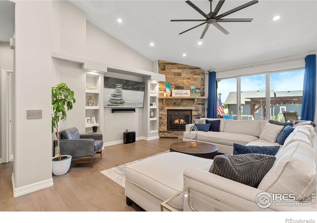 living room with wood finished floors, recessed lighting, a stone fireplace, baseboards, and ceiling fan