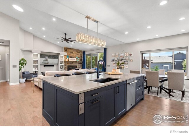 kitchen with lofted ceiling, light wood-style flooring, a fireplace, and a sink