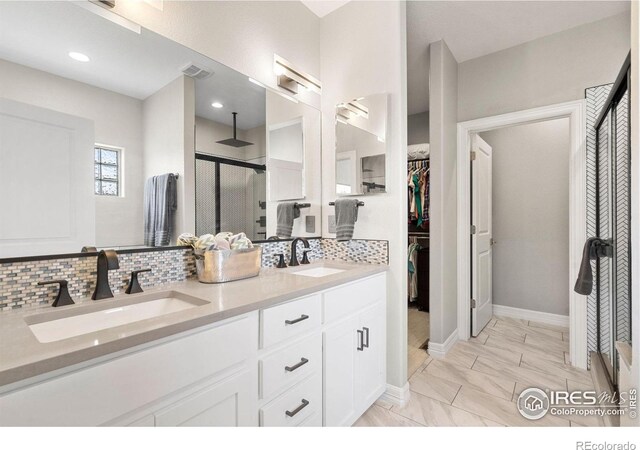 bathroom with double vanity, a stall shower, backsplash, and a sink