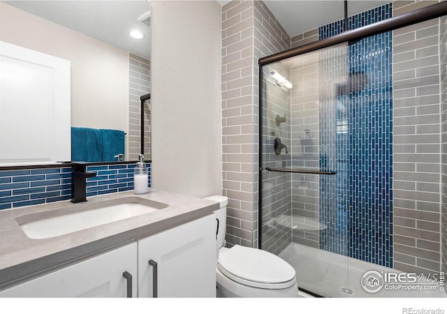 bathroom featuring backsplash, a stall shower, vanity, and toilet