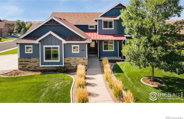 craftsman house with a standing seam roof, stone siding, board and batten siding, a front yard, and metal roof