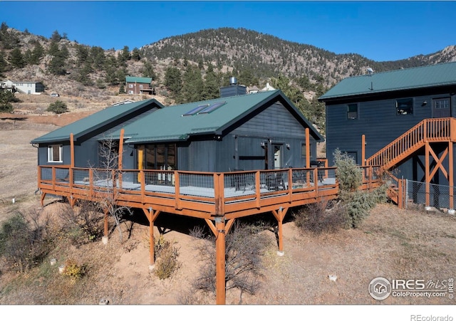 back of property featuring a deck with mountain view and metal roof