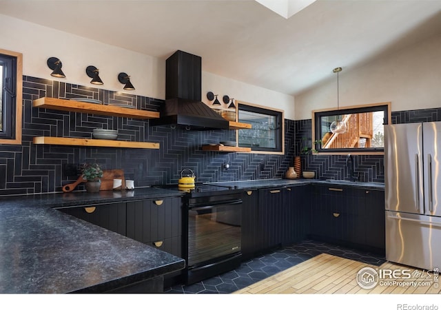 kitchen with open shelves, dark countertops, freestanding refrigerator, and island range hood