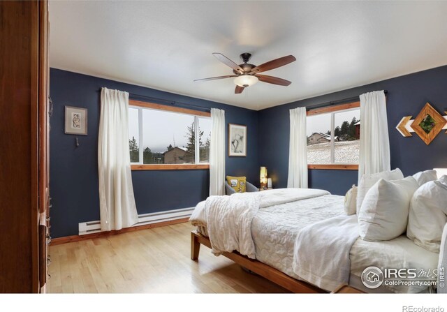 bedroom featuring a ceiling fan, light wood-style floors, and a baseboard radiator