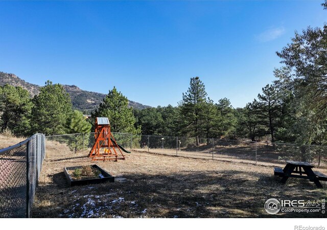 view of jungle gym featuring fence and a mountain view