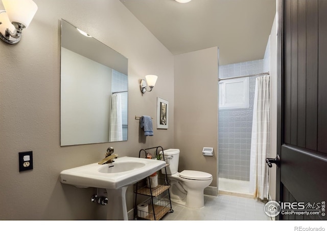 full bath featuring a shower with shower curtain, toilet, tile patterned flooring, and a sink