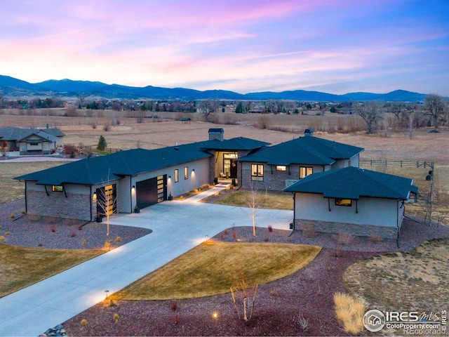 view of front facade featuring concrete driveway, a garage, a mountain view, and stone siding