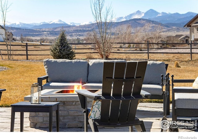 view of patio / terrace featuring fence, a mountain view, and an outdoor fire pit