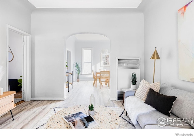 living area featuring heating unit, wood finished floors, and arched walkways