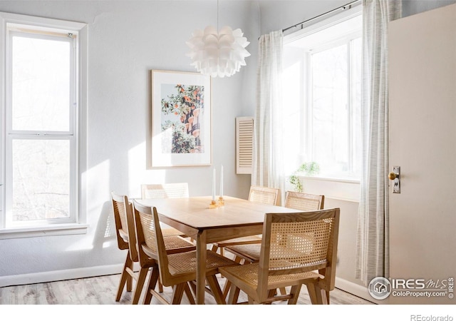 dining space featuring plenty of natural light, baseboards, an inviting chandelier, and wood finished floors