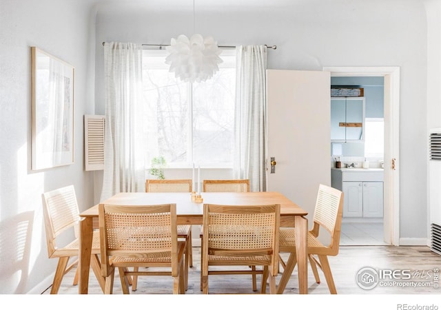 dining space featuring baseboards, light wood-type flooring, and a chandelier