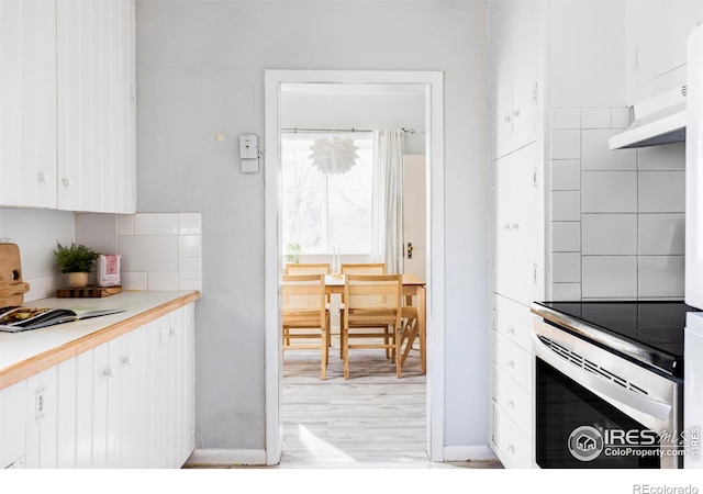 kitchen featuring backsplash, stainless steel range with electric cooktop, white cabinetry, and light countertops