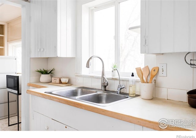 kitchen featuring a sink, white cabinets, and light countertops