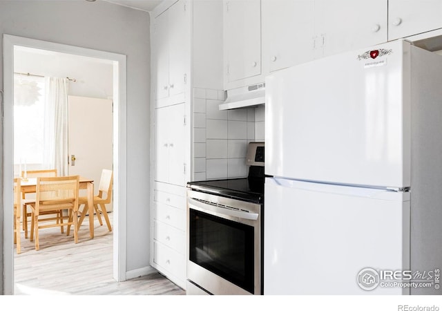 kitchen with light wood finished floors, tasteful backsplash, under cabinet range hood, freestanding refrigerator, and electric stove