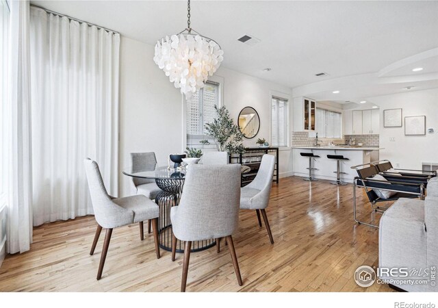 dining space with light wood-style flooring, a notable chandelier, recessed lighting, and visible vents