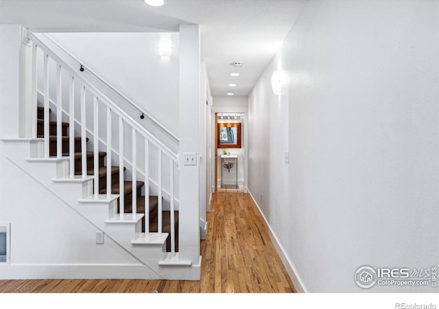 stairway with recessed lighting, wood finished floors, and baseboards