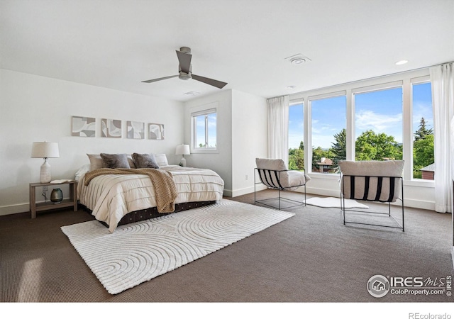 carpeted bedroom featuring baseboards, multiple windows, and ceiling fan