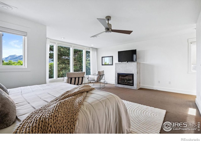 carpeted bedroom with a glass covered fireplace, multiple windows, and baseboards