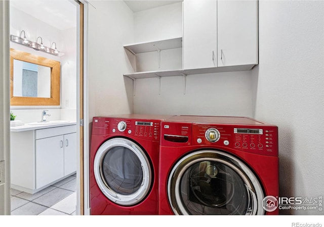 laundry area featuring a sink, cabinet space, light tile patterned flooring, and washing machine and clothes dryer