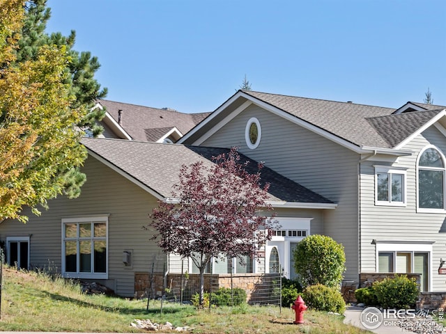 traditional home featuring stone siding and a shingled roof