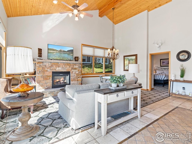 living room featuring a stone fireplace, ceiling fan with notable chandelier, wood ceiling, and baseboards