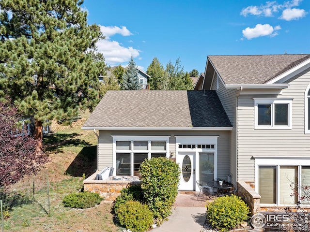 view of front of house with stone siding and roof with shingles