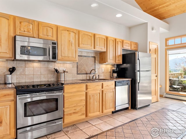 kitchen featuring a sink, a baseboard heating unit, stainless steel appliances, light tile patterned floors, and decorative backsplash