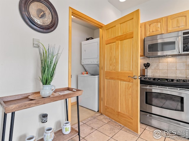 kitchen with light brown cabinetry, backsplash, appliances with stainless steel finishes, light tile patterned flooring, and stacked washer / dryer