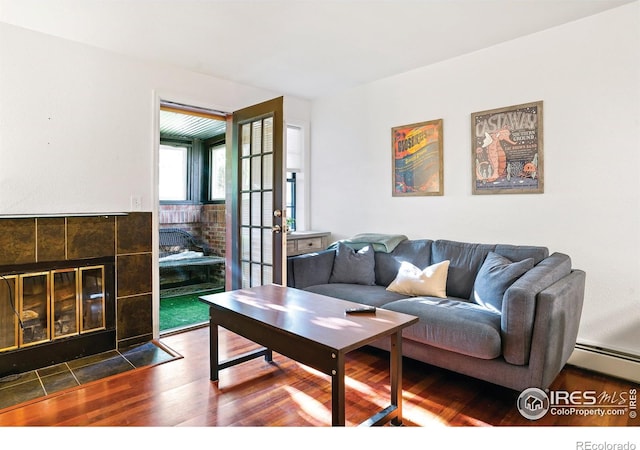 living area with baseboard heating, dark wood finished floors, and a fireplace