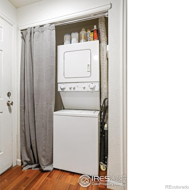 laundry area featuring laundry area, wood finished floors, and stacked washer and dryer