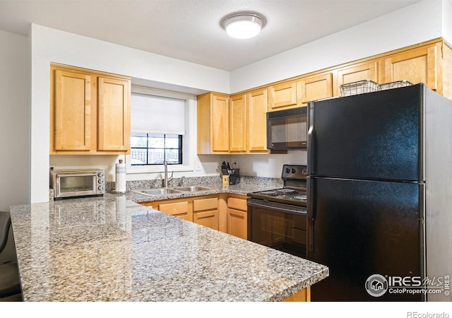 kitchen featuring light brown cabinets, a toaster, a sink, a peninsula, and black appliances