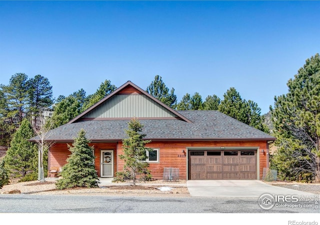 view of front of house with driveway, an attached garage, and a shingled roof