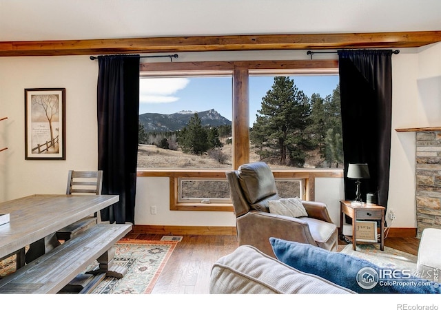 living area with a wealth of natural light, a mountain view, visible vents, and wood finished floors