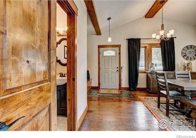 foyer featuring an inviting chandelier, vaulted ceiling with beams, baseboards, and wood-type flooring